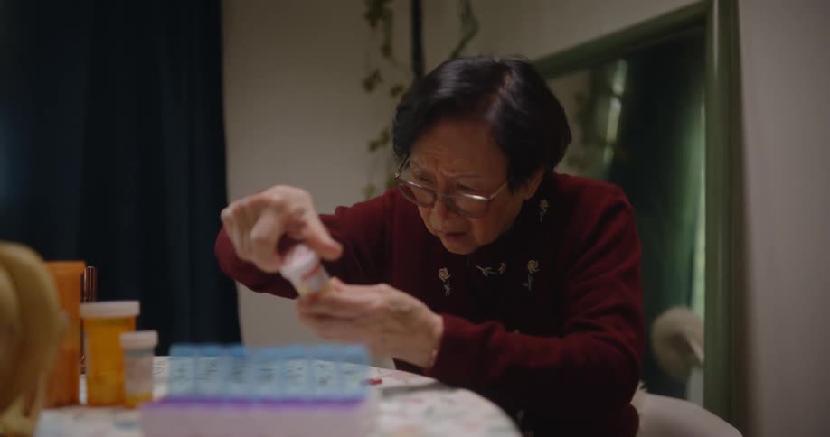An asian women frets while examining her medication bottles