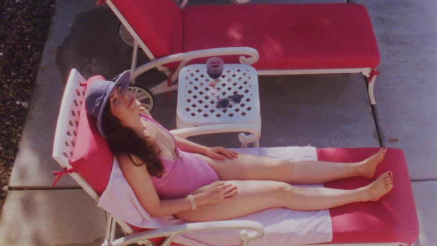 Woman in pink swimsuit relaxing on red lounge chair