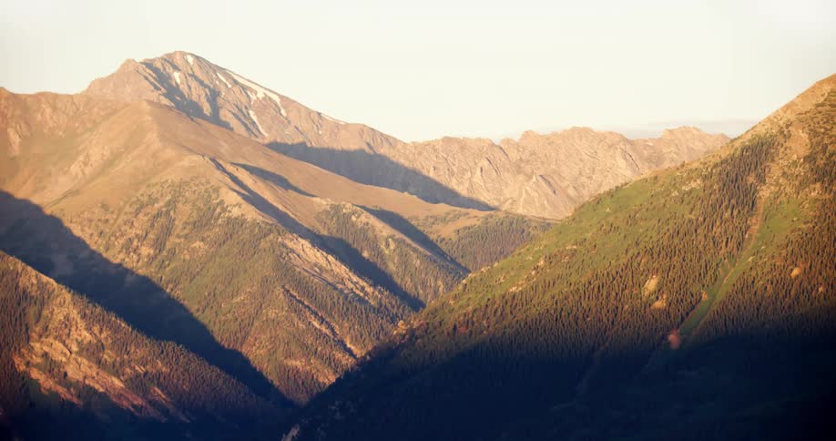 Mountain range with bright sunny peaks and contrasting dark shadowy base