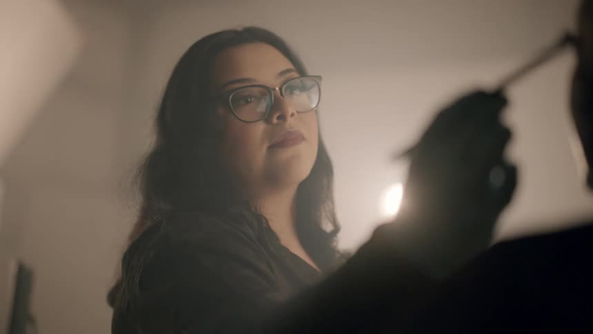 Woman concentrated while doing makeup on another woman inside a studio