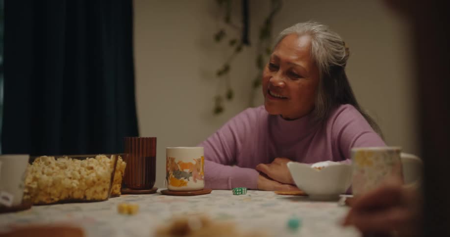 Friends sitting at a table with cups and popcorn playing and having fun with dice