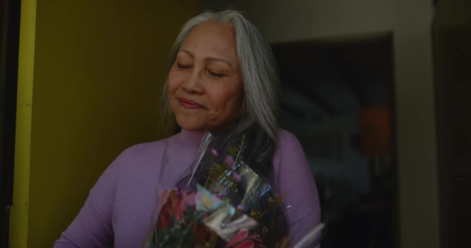 An old man gives a happy but slightly suspicious woman some flowers