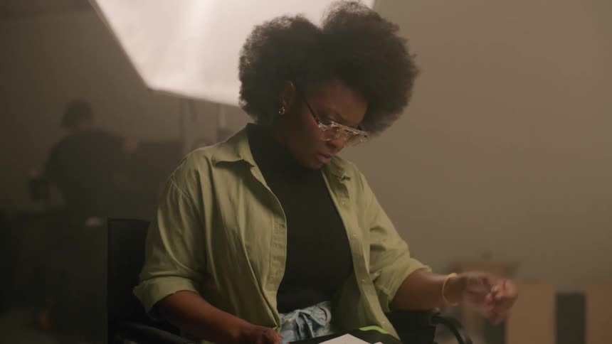 A black woman reads some papers and uses a pen to cross out text