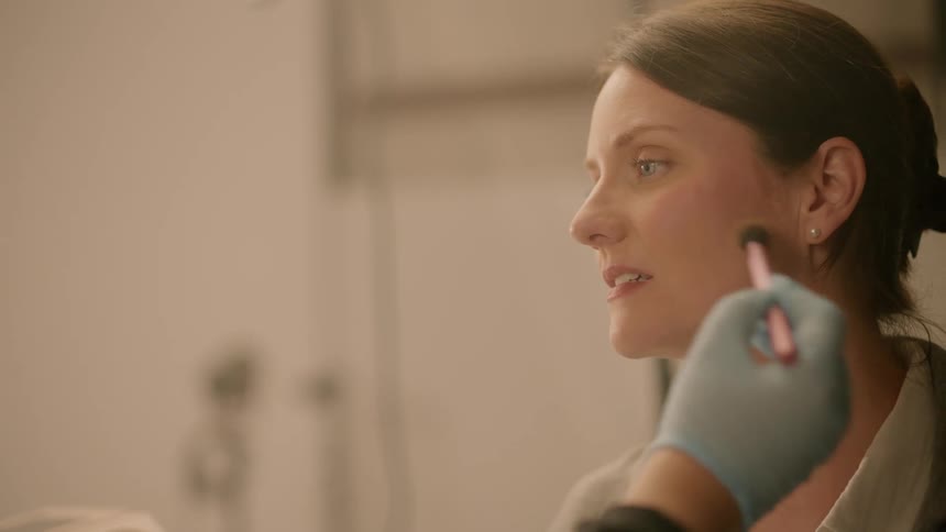 A woman applies makeup to another womans face