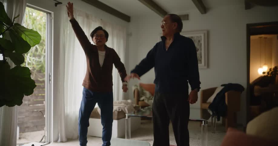 Two elderly asians exercise together in a room