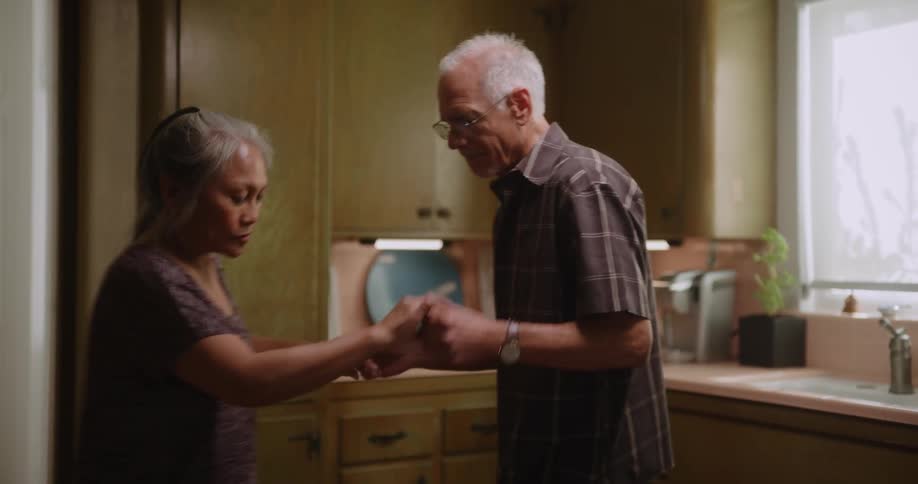 Elderly man and woman dance together in the kitchen