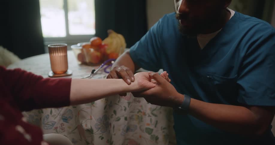 Nurse checking an elderly womans pulse as they talk