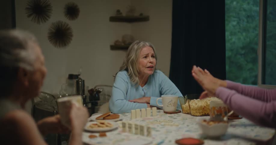 Three women drink and chat around a dining room table