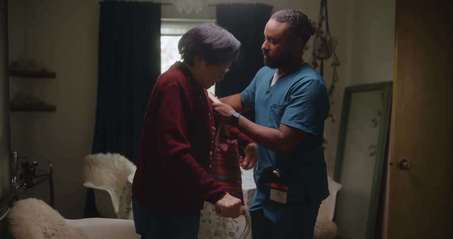 Nurse helping an elderly woman to get up from her chair and walk