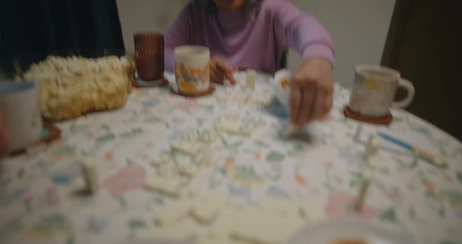 Portrait of three female friends sitting at a table drinking cups of tea and playing dominoes