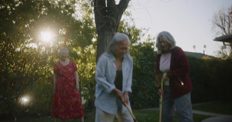 Three older women playing croquet on the lawn having fun
