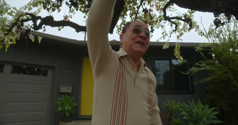 Father giving his son a boost in the backyard while he is on a scooter and then waves his hand goodbye