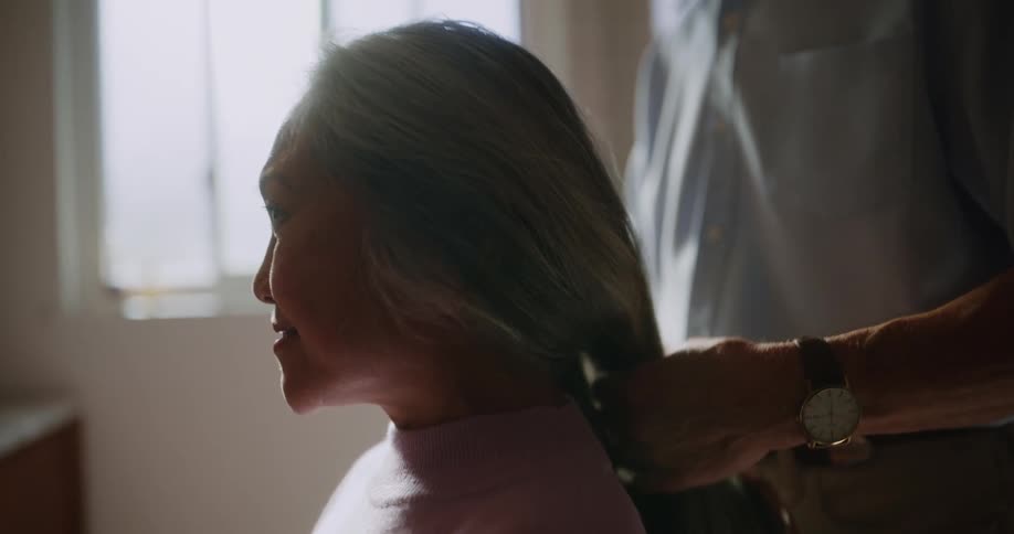 A man is brushing a womans hair and kisses her