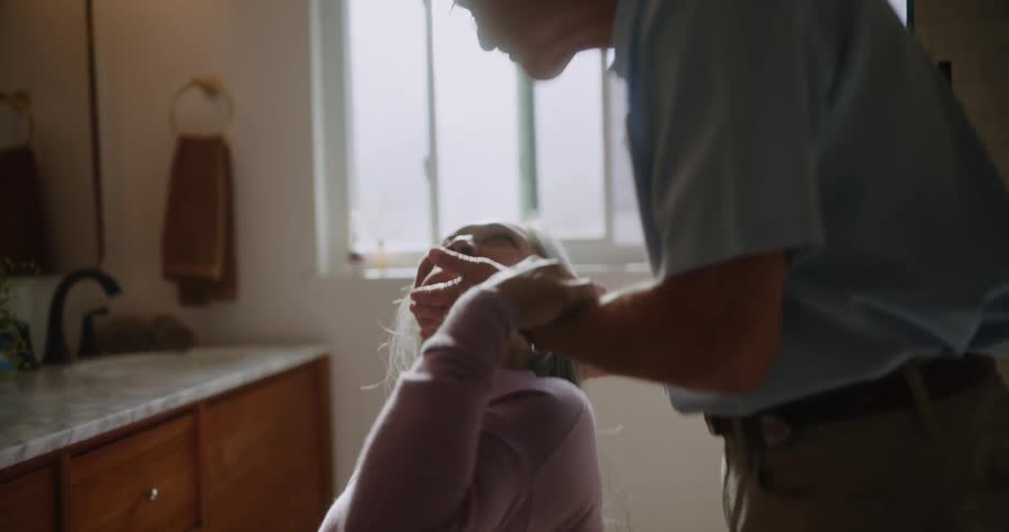 A man brushes a womans hair and then kisses her
