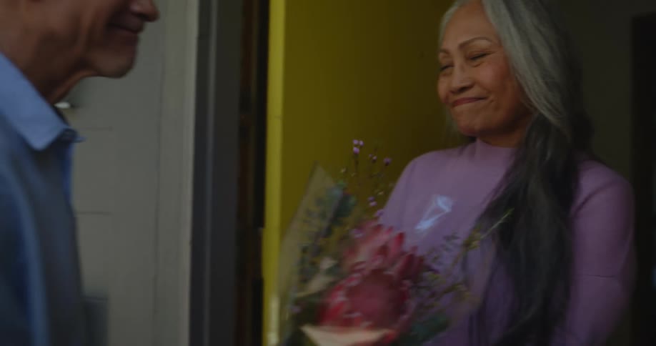 A woman accepts flowers from a man with some reserve