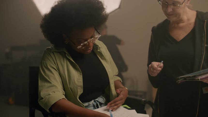 Two women discuss a script in a studio