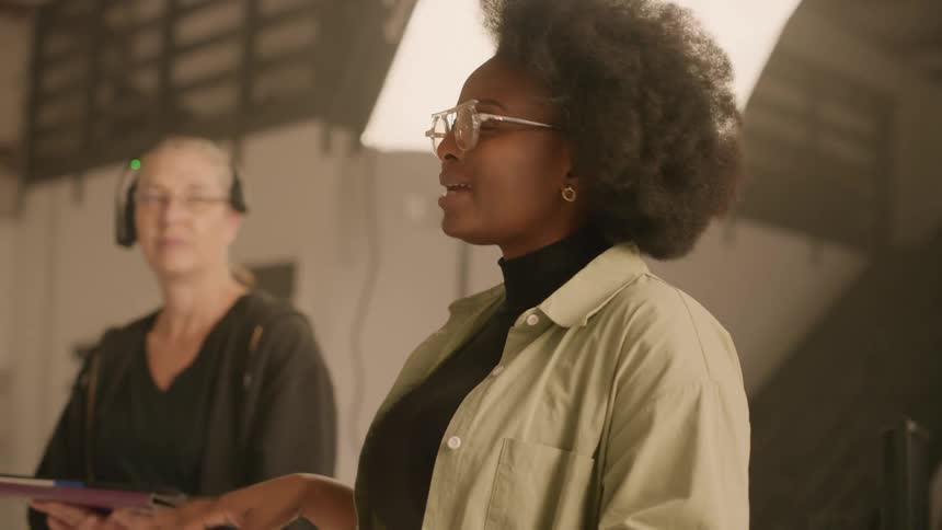 Woman holding a paper and talking while standing in a studio