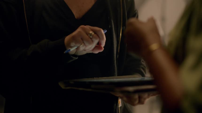 Two coworkers talk while using a tablet