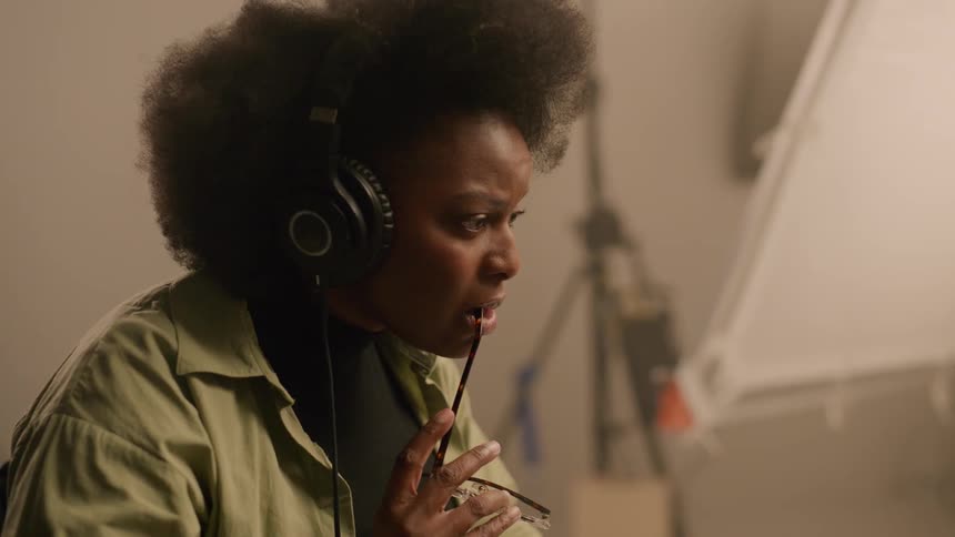 Woman sitting down while wearing headphones alone in a room