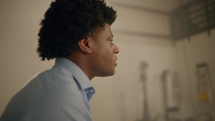 A black man talks while sitting in a room