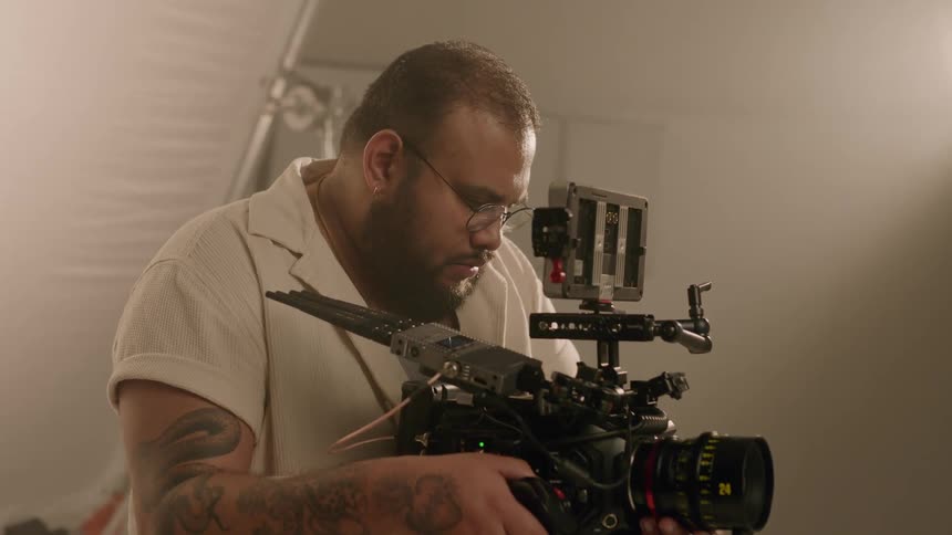 Man inside a studio holding a professional camera and adjusting its lens