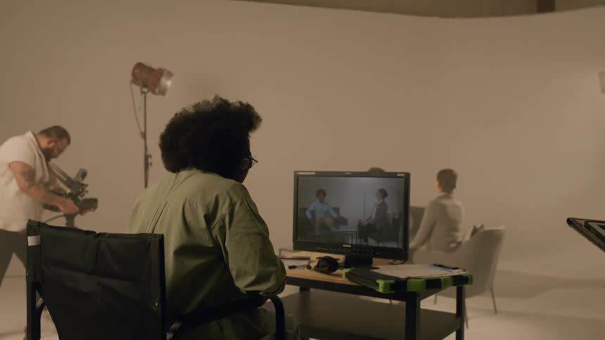 Recording of two people in a studio with people around them monitoring a program