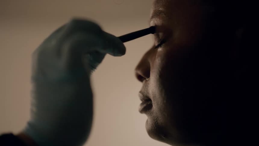 A woman is getting her makeup done by another person