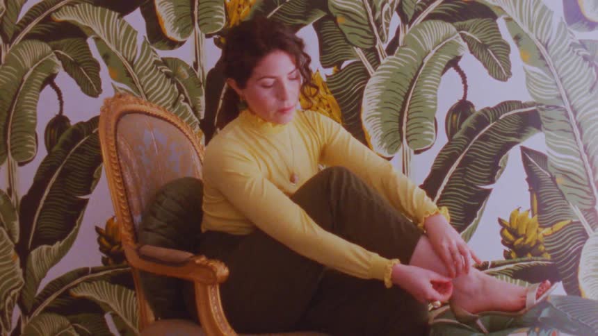 Woman sitting on a chair tying the clasp of her high heels
