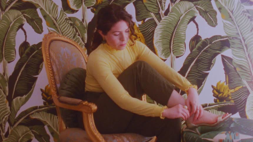 A woman adjusts a shoe strap