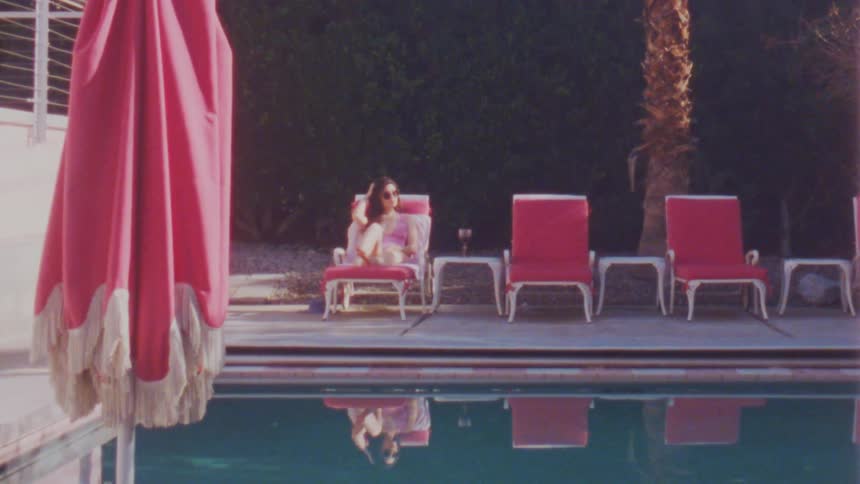 Young woman in pink bikini sitting poolside on a chaise lounge