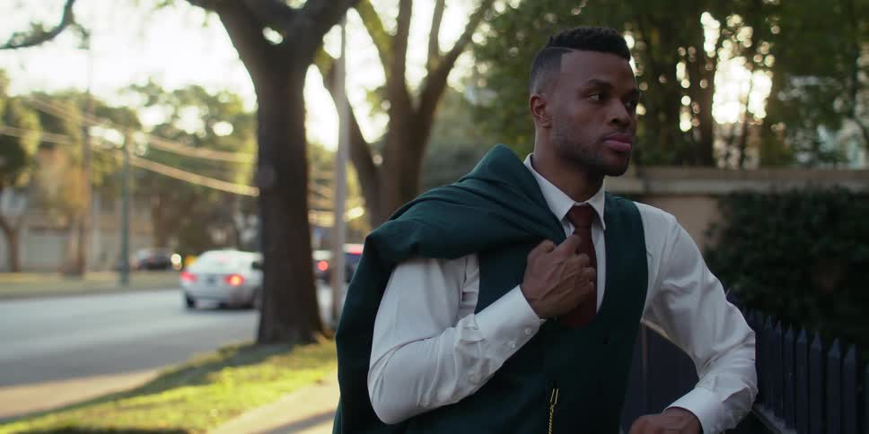 A black man stands outside near a street