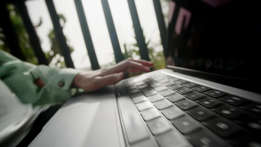 Hand of a person opening a laptop on the balcony of the house
