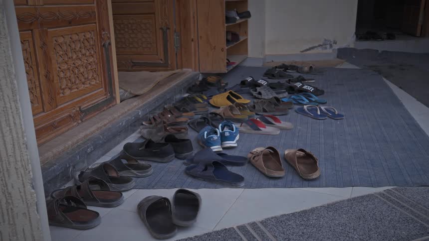 Various sandals laying on large doormat in front of door on porch