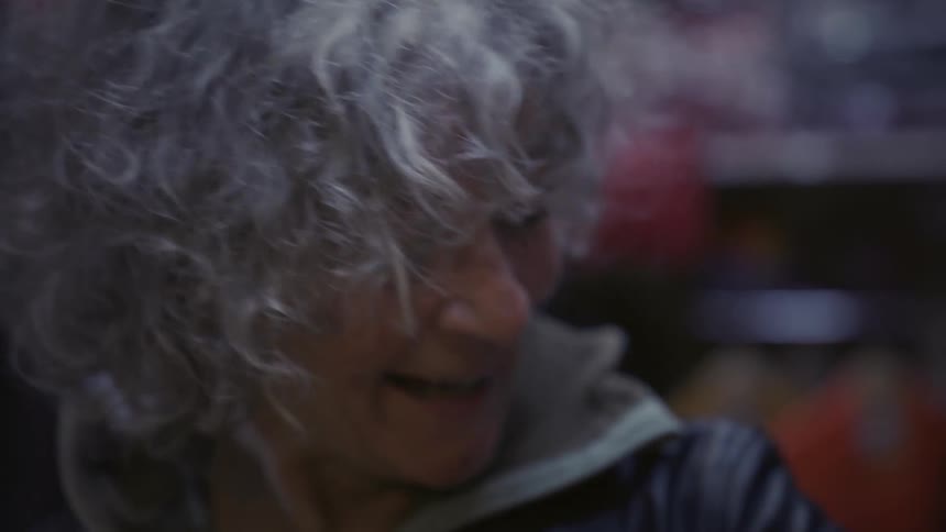 A woman laughs as a man runs a burning lighter over her coat sleeve