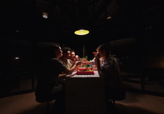 Group of friends sitting at a table at night talking and eating