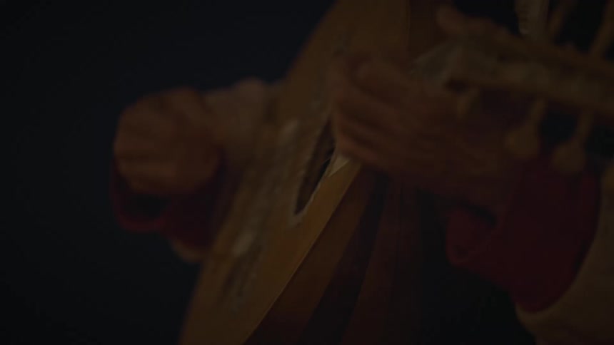 A man is playing an instrument while sitting outdoors at night time