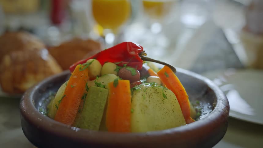 A persons fingers removing the lid from a bowl presenting a dish with steamed vegetables