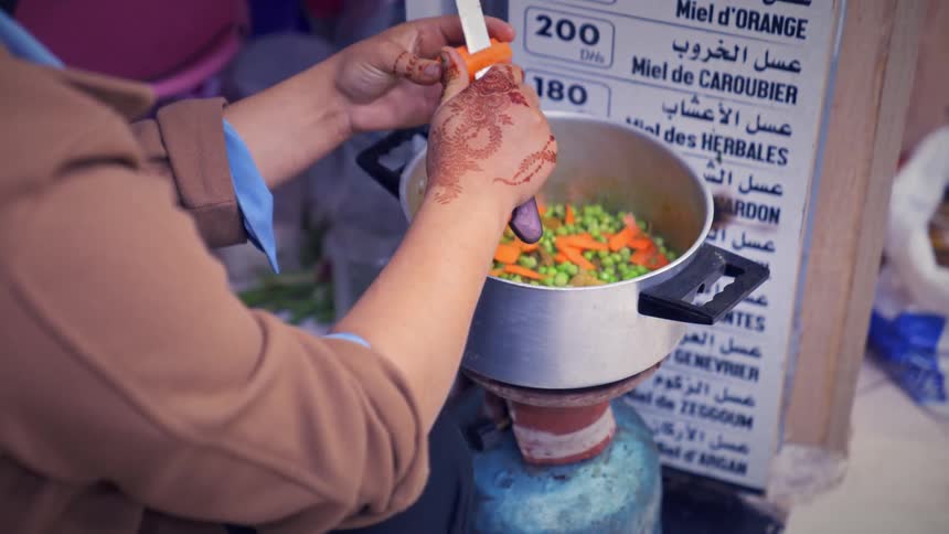 A person with henna tattoos cooking in the street