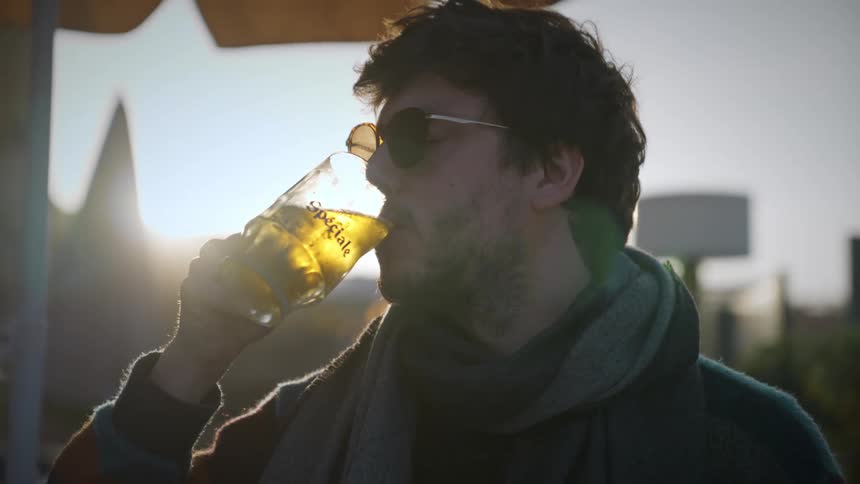 Man is drinking an alcoholic beverage while standing outdoors