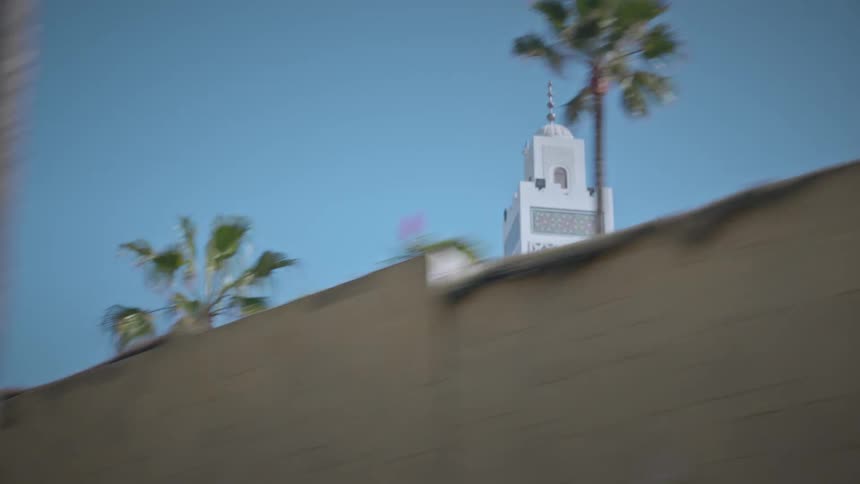A mosque tower behind a concrete wall