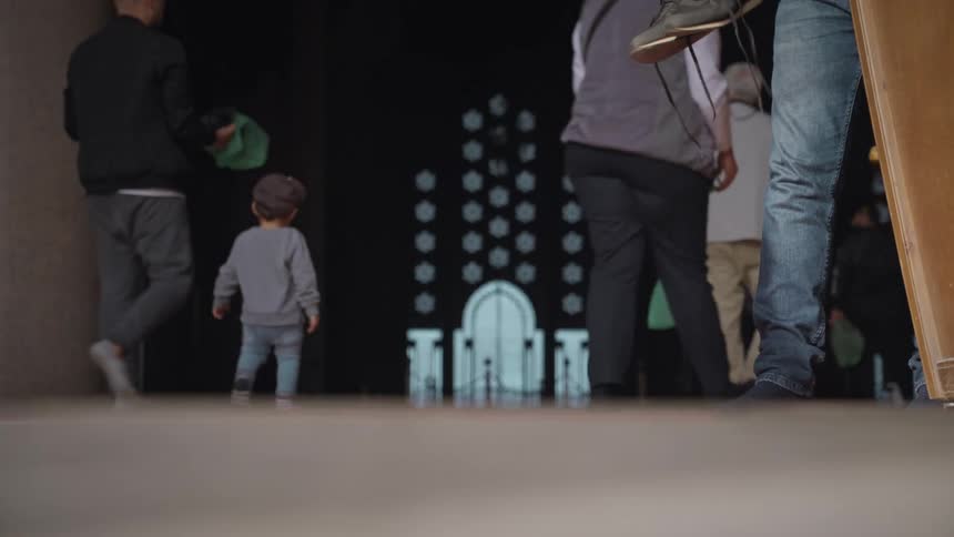 Person picking up his pair of sneakers and then entering a temple with a crowd of people