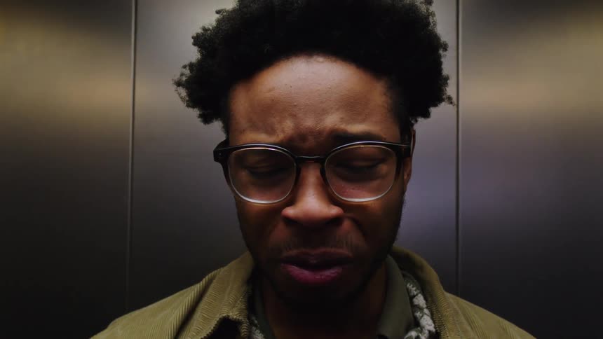 Man is yawning while standing inside an elevator