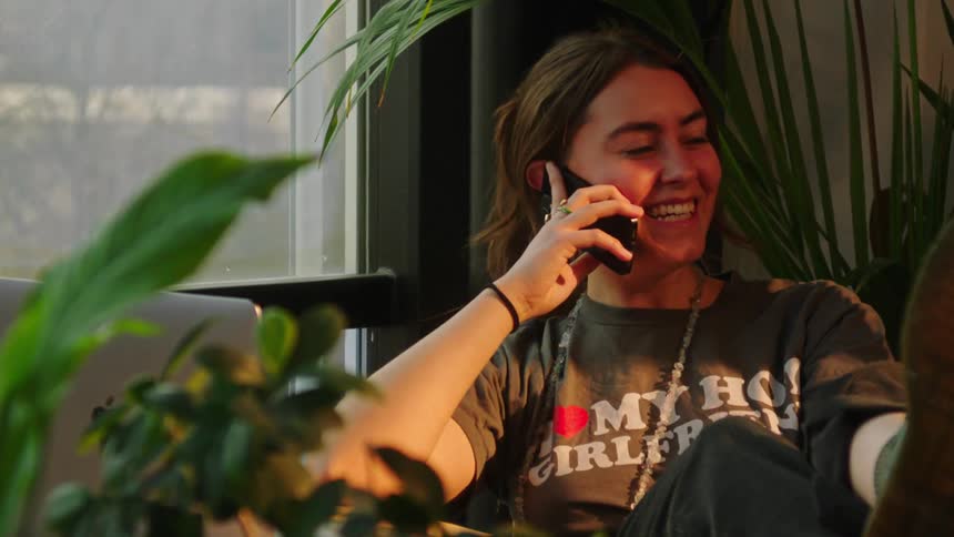 Young woman sitting smiling talking on smartphone