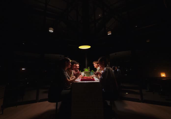 Group of friends sitting at a table in a restaurant at night talking