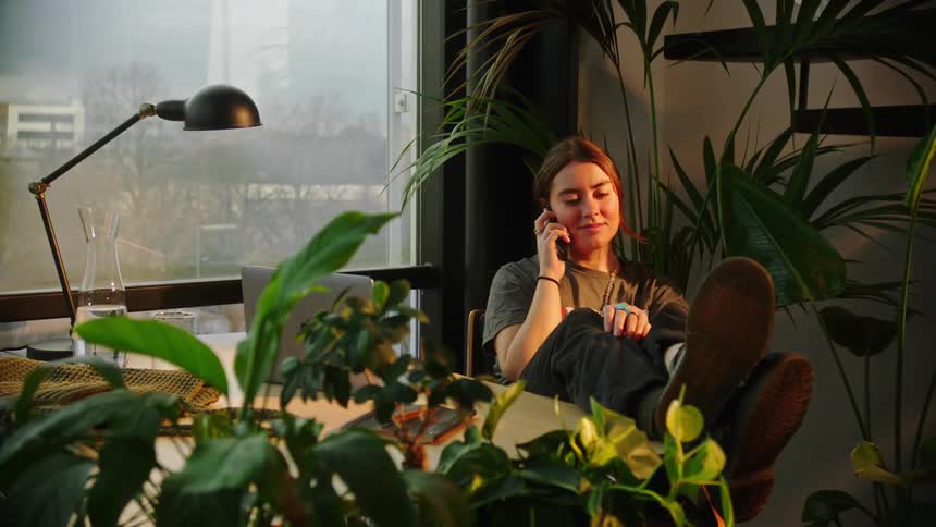 Woman sitting at a desk and talking on a cell phone