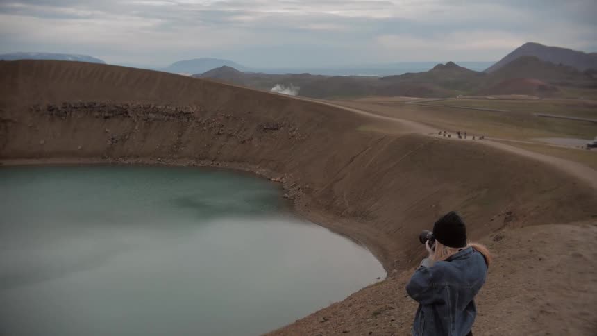 A female taking a picture of a lake