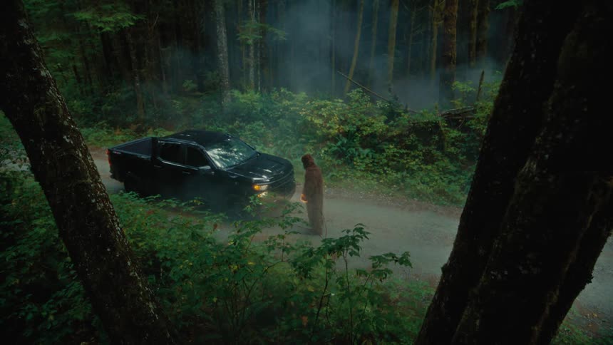A person stands moving nervously in front of a black pickup truck