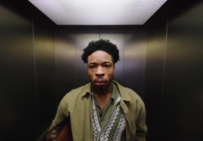 A man waiting inside an elevator is yawning from being tired