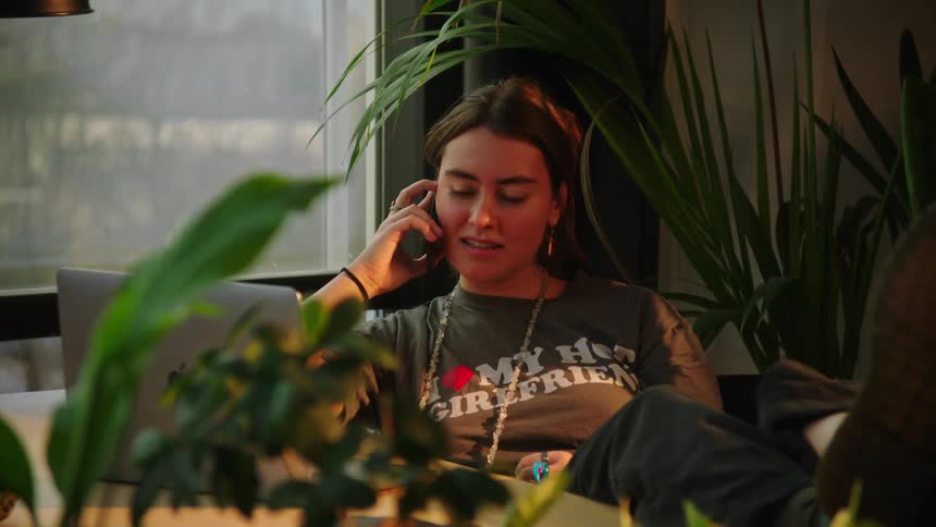 A woman lounges at a desk while on the phone
