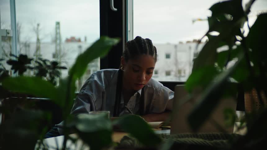 Woman is typing on a computer and writing notes down on paper